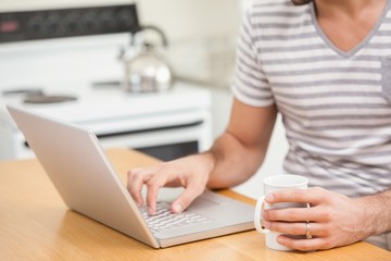 Young man using laptop while having coffee