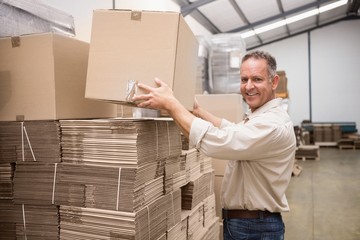 Smiling warehouse worker taking a box
