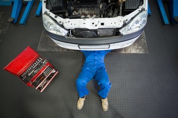 Mechanic lying and working under car