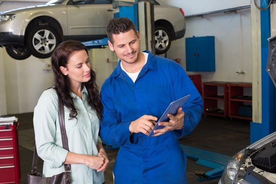 Mechanic showing tablet pc to customer
