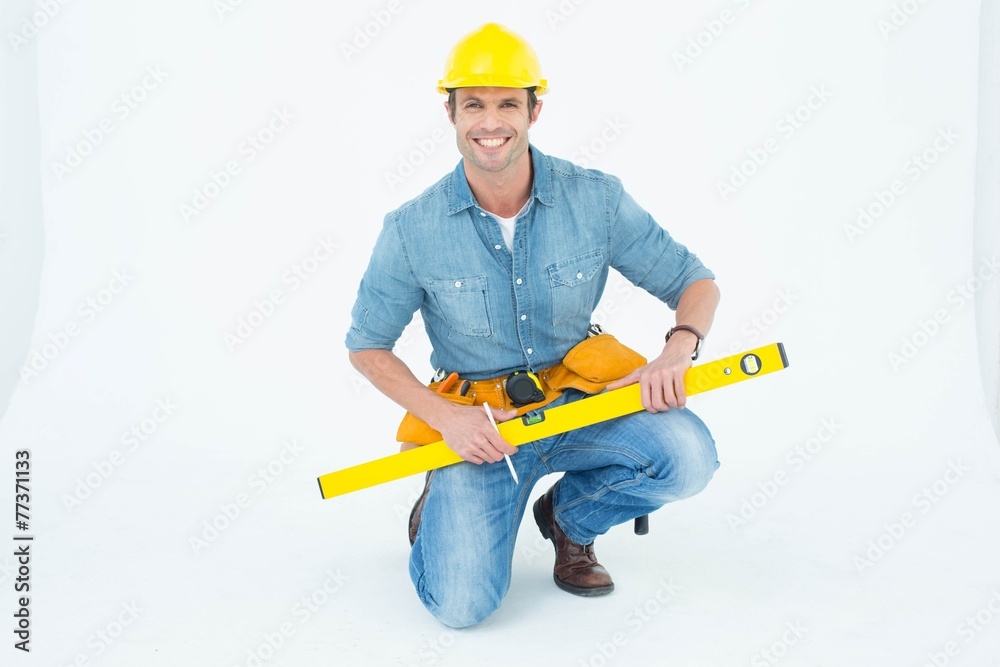 Poster worker using spirit level while kneeling over white background