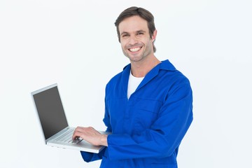 Handsome mechanic using laptop over white background