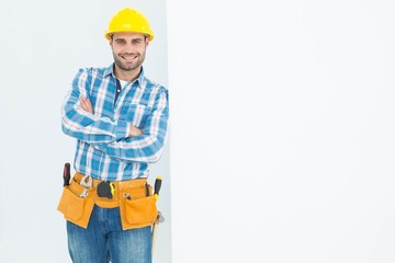 Confident repairman leaning on blank billboard