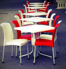 Red and white chairs with tables in an outdoor café on the road