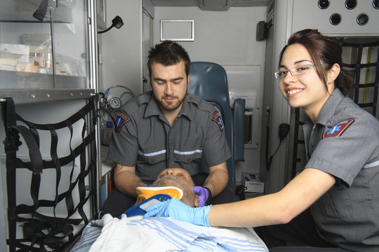 professional paramedics giving unconscious young woman first aid