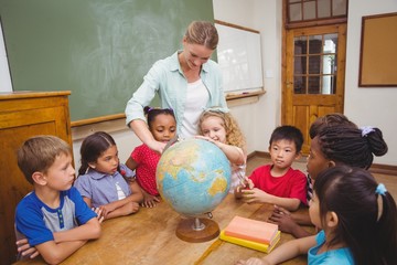 Fototapeta premium Cute pupils and teacher in classroom with globe