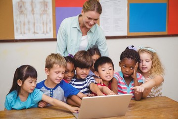 Fototapeta na wymiar Teacher and pupils looking at laptop