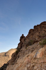 Fototapeta na wymiar Rocky cliff with blue sky, Jabal Nakhal, Sultanate of Oman