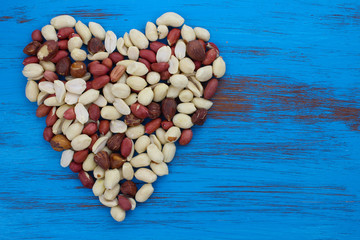 peanuts nuts in heart shape on blue rustic wood background.