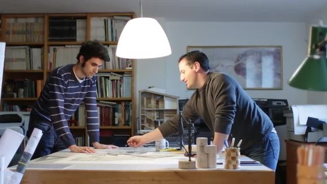 Two architects examining a plan in an office (dolly)