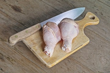 Chicken thighs and knife on chopping block