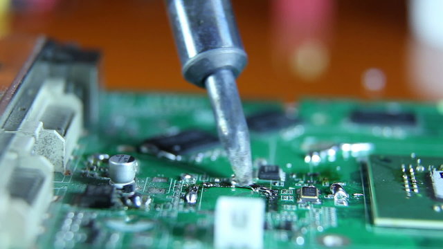 Shot of a man solder a  chip on a graphics card
