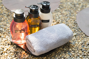 Amenity set : Shampoo, bath gel, soap and lotion on pebbles floor