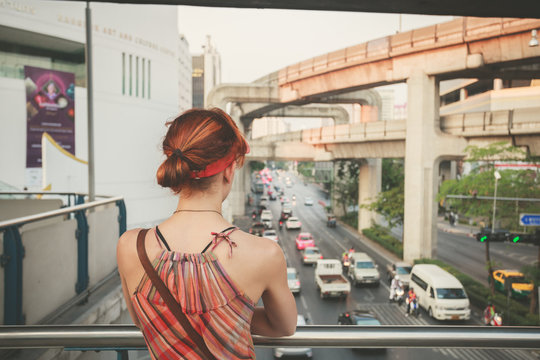 Young woman looking at traffic in Bangkok