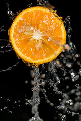 Fototapeta na wymiar orange in water on a black background