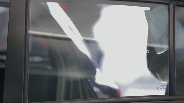Person opens car door and cleans the window with a cloth