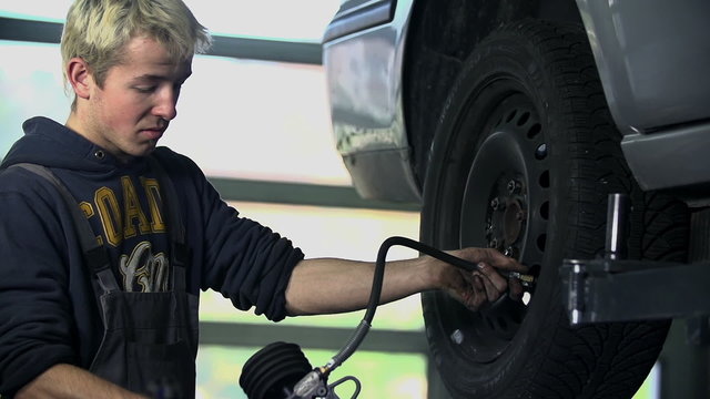 Close shot of mechanic inflating a tire with compressor