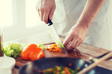 close up of male hand cutting pepper on board