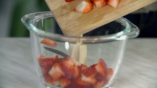 Moving peaces of strawberries into a bowl