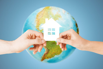 couple hands holding green house over earth globe