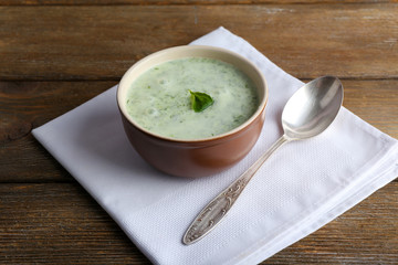 Cucumber soup in bowl on rustic wooden table background