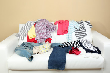Messy clothing on white sofa, on light wall background