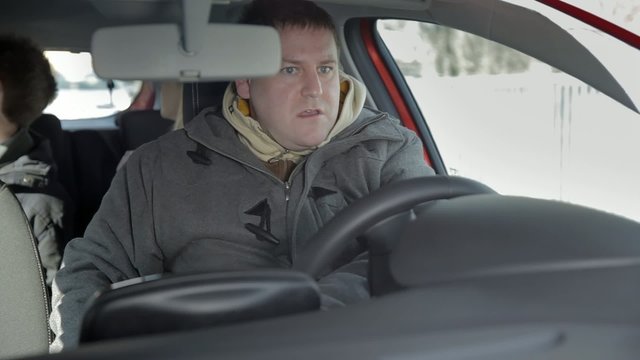 Man starts teh car again and drives in reverse 