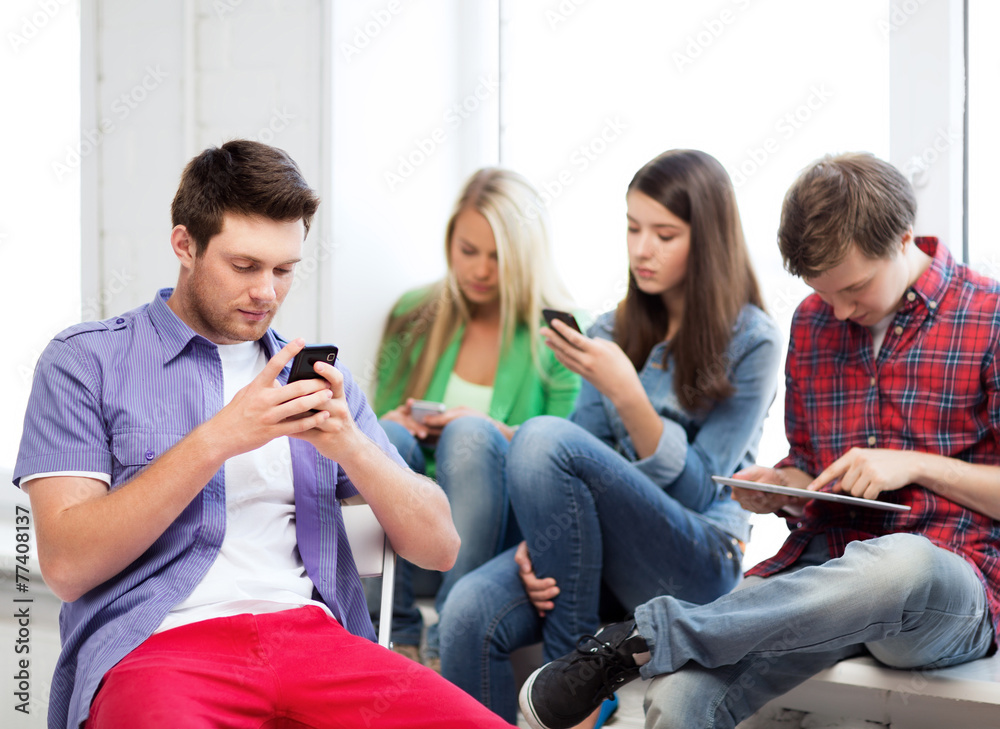 Wall mural students looking into devices at school