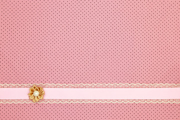 Pink polka dot textile background with ribbon and flower