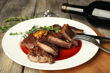 Steak on plate with bottle of wine on wooden background