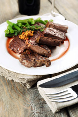 Steak with wine sauce on plate on wooden table