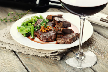 Steak on plate with bottle of wine on wooden background