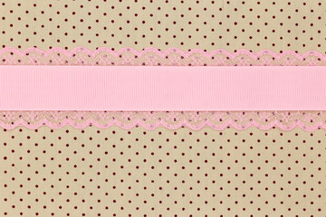 Retro beige polka dot textile background with pink ribbon