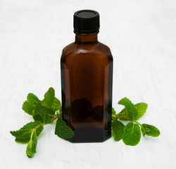 Bottle of mint oil and fresh mint
