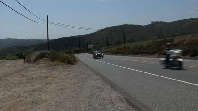 Shot of a road with motocyclists and some cars. Longest bicycle competition over United States of America - RAAM in 2009.