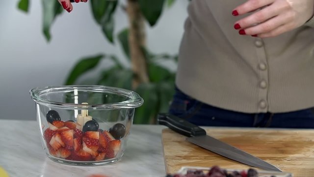 Throwing grapes in glass bowl