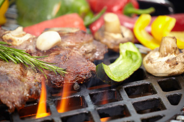 T-bone steak on the barbecue grill with vegetable spears in the