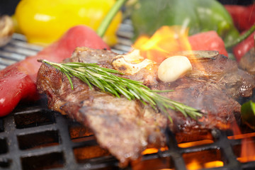 T-bone steak on the barbecue grill with vegetable spears in the