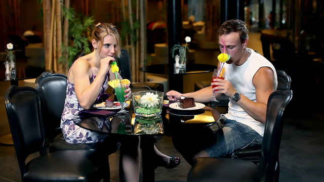 young couple drinking coctail and eating cake at pool