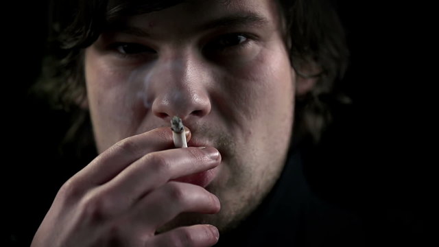 Young man inhales a cigarette smoke in slow motion 