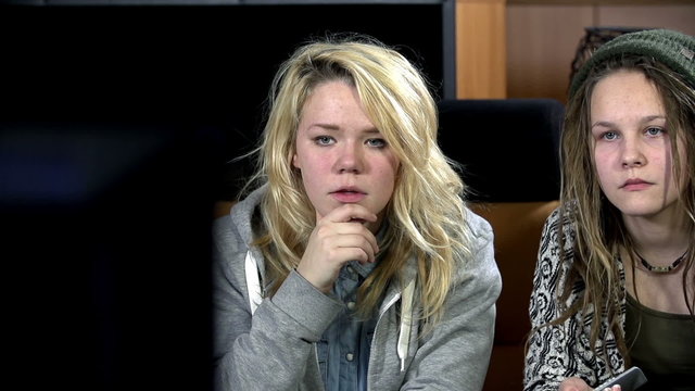 Girls with deadpan faces are bored as hell watching television