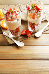 Healthy layered dessert with muesli and strawberries on table