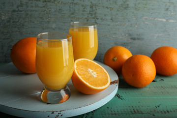Glass of orange juice with slices on color wooden background