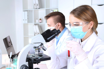 Young female and male scientists  with microscope in laboratory