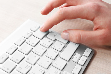 Female hand with keyboard on wooden desktop background