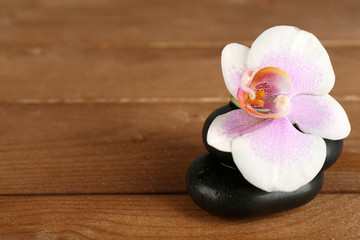 Spa stones with orchid on wooden background