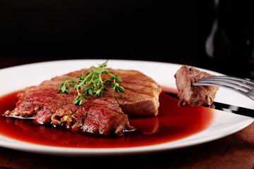 Grilled steak in wine sauce with bottle of wine