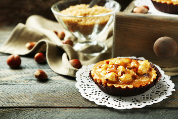 Mini cakes with nuts on napkin on wooden background