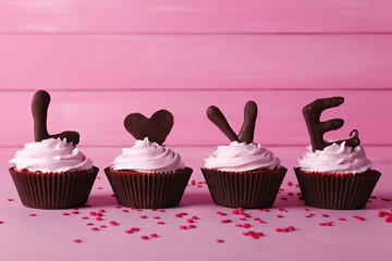 Delicious Valentine Day cupcake on pink wooden background