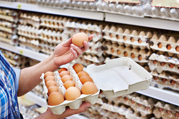 In hands of woman packing eggs in supermarket